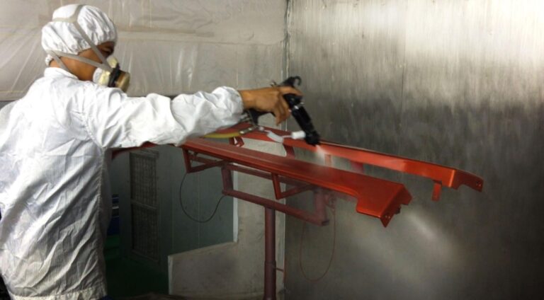 Operator spray painting parts inside a paint booth